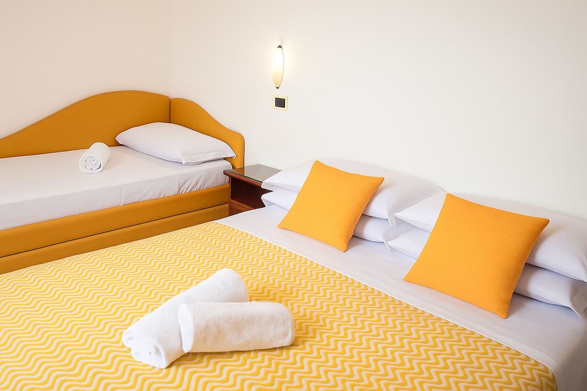 Een hotelkamer met een bed, een bank en een wandlamp.