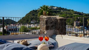 A rooftop terrace with a view of a hillside and cityscape.