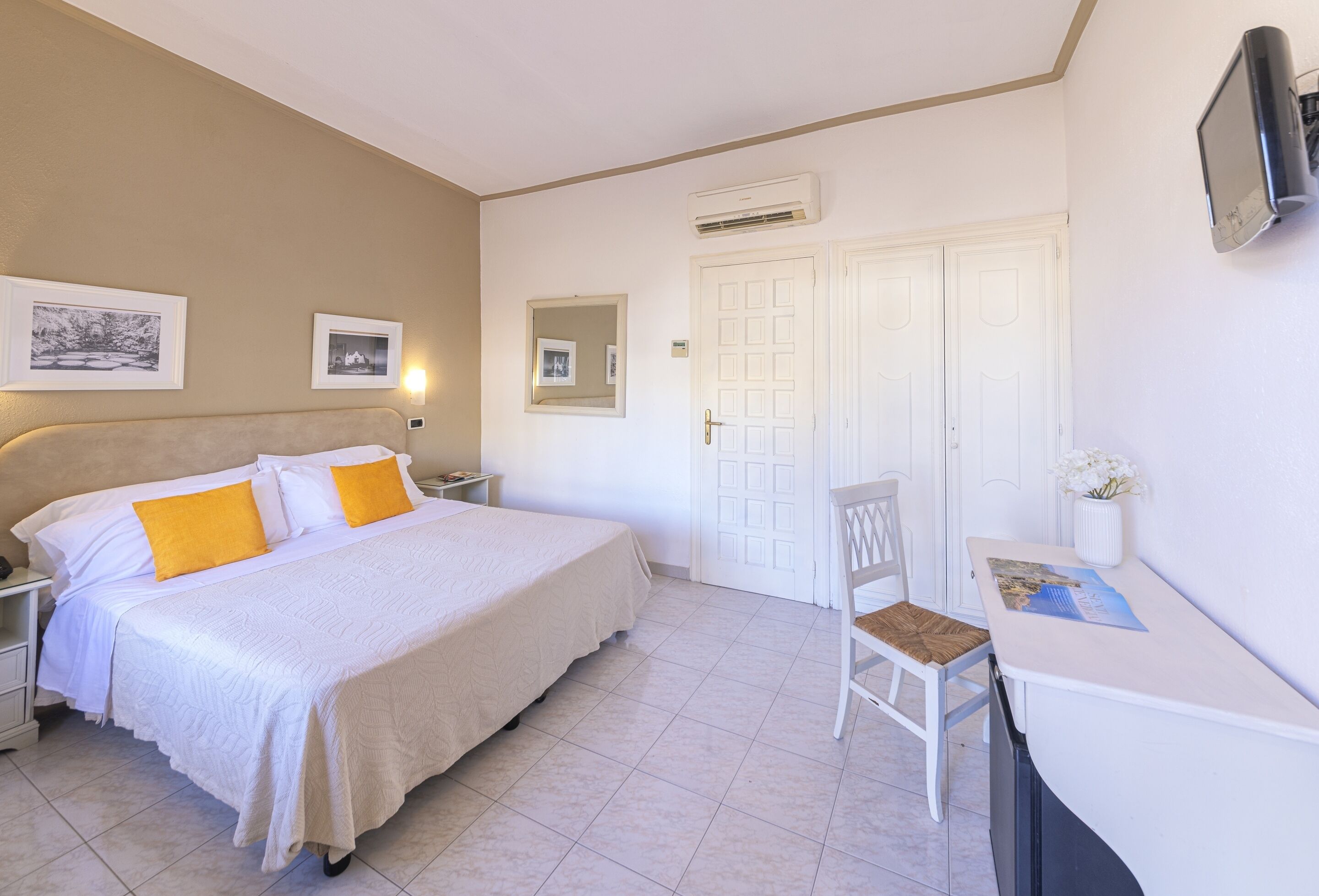 A bedroom with a bed, nightstands, a chair, a desk, and a door.