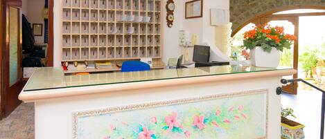 Una reception con un piano in vetro, una sveglia, un computer e una pianta in vaso.