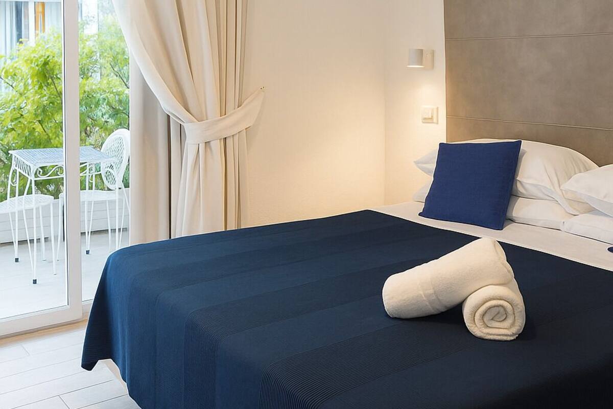Een hotelkamer met een bed, uitzicht op de omgeving en een balkon.