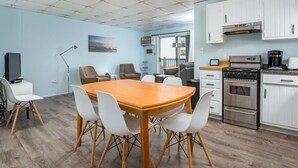A modern kitchen with white cabinets, a stove, and a coffee maker. - Oceanfront condos with 3 night minimum rentals and linens included! (Ocean City)