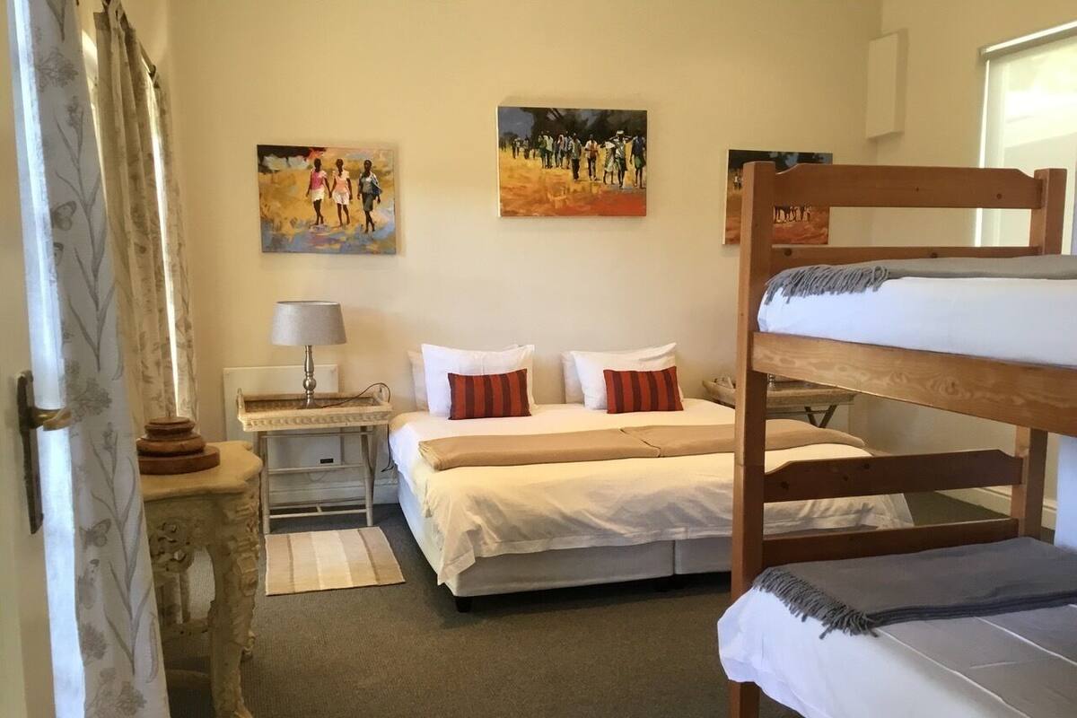 A bedroom with a bunk bed, a bedside table with a lamp, and two paintings on the wall.