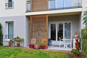 A modern two-story building with a balcony, potted plants, and a small outdoor seating area. - Domitys Les Rives du Cher (Montlucon)