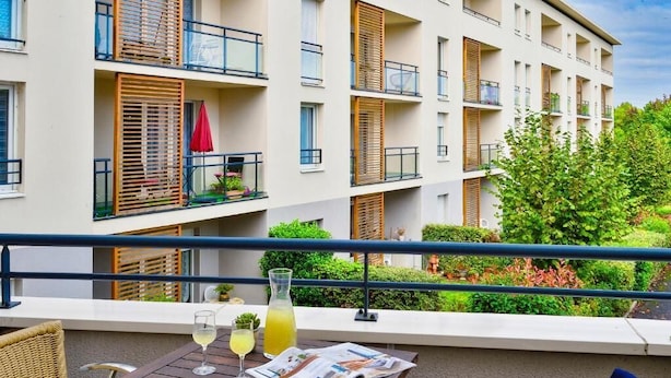 A balcony with a wooden table, two glasses of drink, and a newspaper. - Domitys Les Rives du Cher (Montlucon)