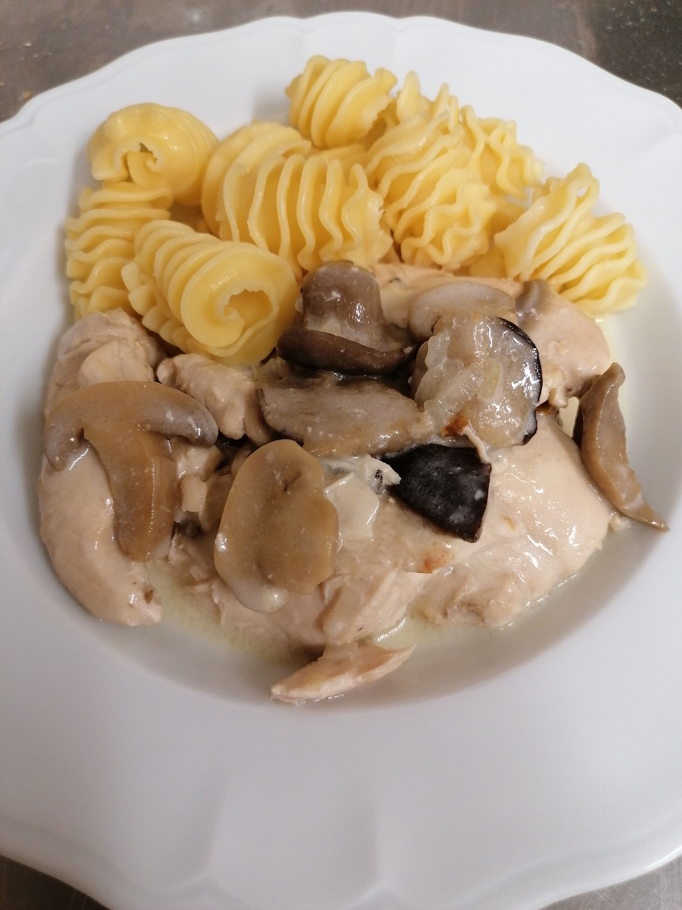 Un plato de comida con pollo, champiñones y pasta.