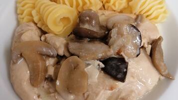 Un plato de comida con pollo, champiñones y pasta.