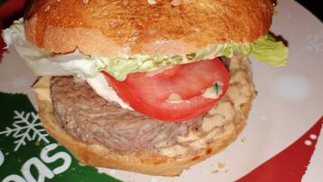 A hamburger with lettuce, tomato, and a sesame seed bun on a plate.