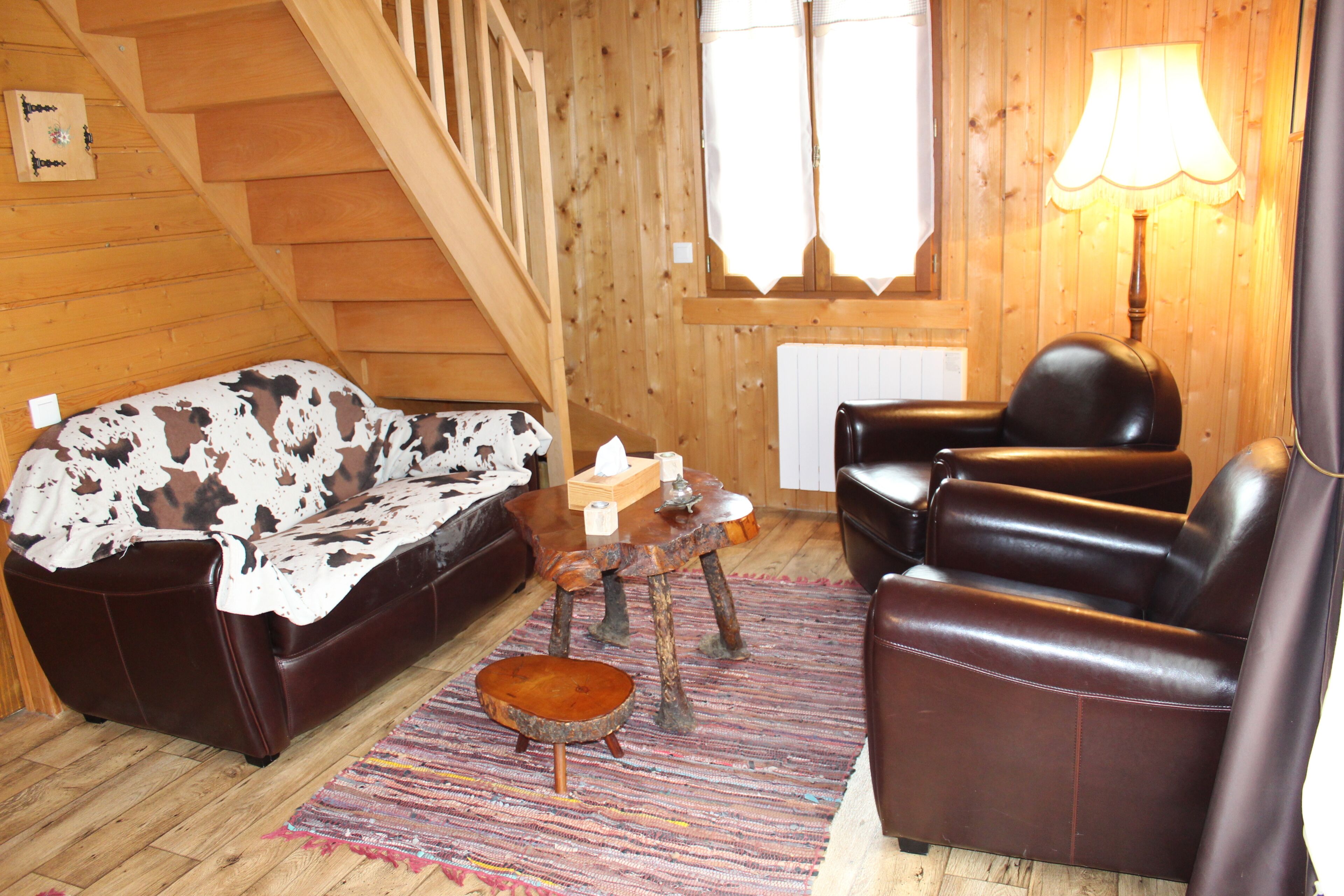 A wooden interior with a sofa, a chair, a small table, and a lamp.
