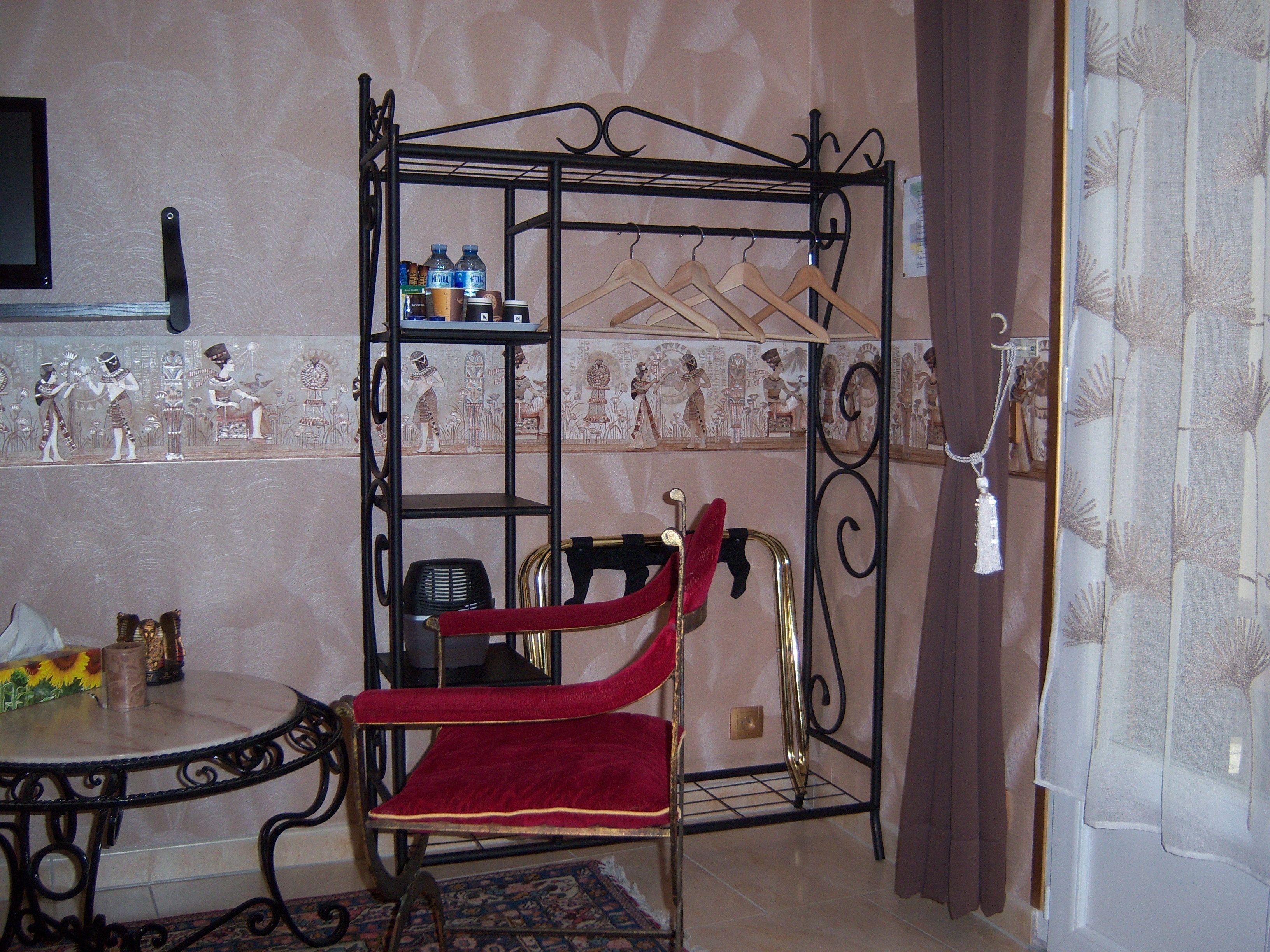 A room with a metal chair, a small table, and a metal rack with hangers.