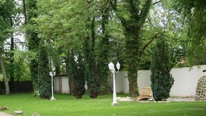 A well-maintained garden with a paved walkway, stone wall, and a wooden bench. - Sawan (Jâlons)