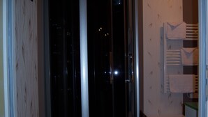 A hotel room with a view of the city at night, a wooden chair, and a towel rack with towels. - Sawan (Jâlons)