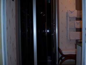 A hotel room with a view of the city at night, a wooden chair, and a towel rack with towels. - Sawan (Jâlons)