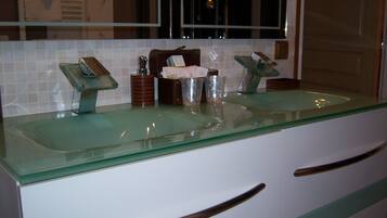 A bathroom with a glass sink, a mirror, and a towel rack.