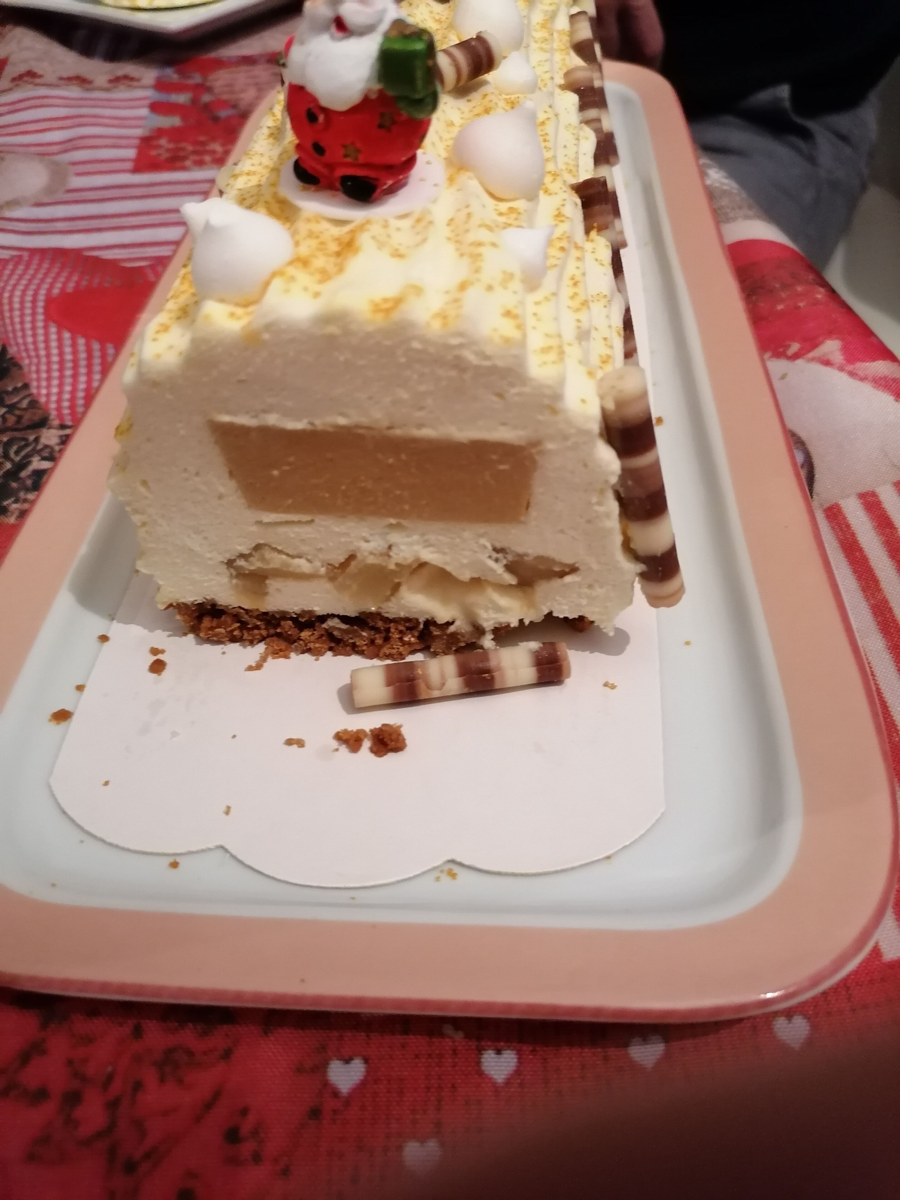 A slice of layered dessert on a white plate with a decorative figure on top.