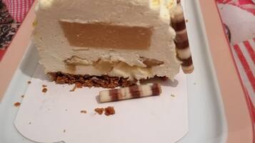 A slice of layered dessert on a white plate with a decorative figure on top.