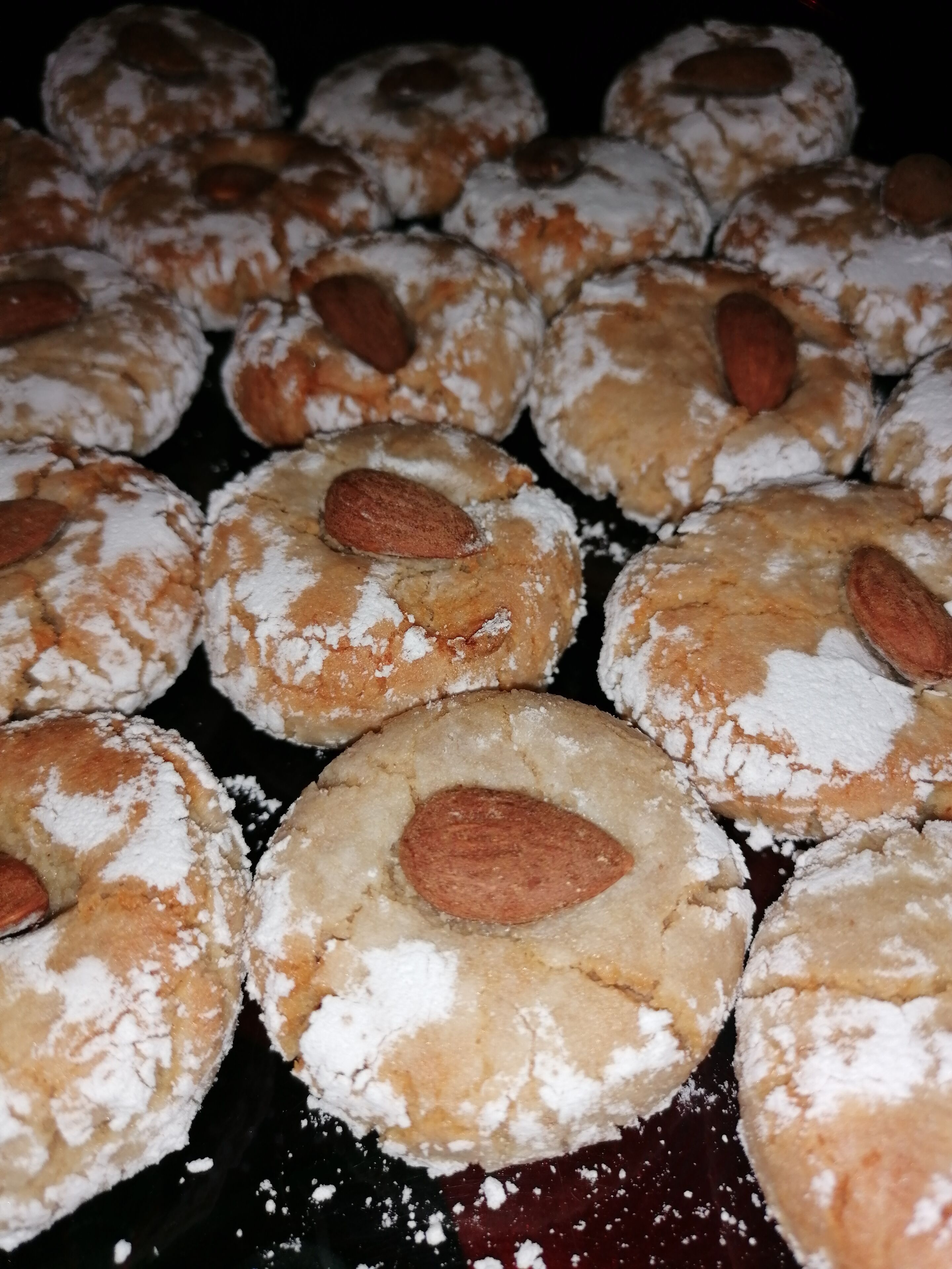 Un vassoio con biscotti rotondi, mandorle e zucchero a velo.
