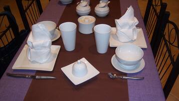 A table set with white dishes, cups, and cutlery, arranged for a meal.