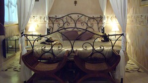 A bed with a canopy, two bedside lamps, and two wicker chairs in a room with patterned wallpaper and a tiled floor. - Sawan (Jâlons)