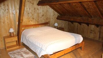 A wooden-framed bedroom with a bed, nightstands, and a rug.