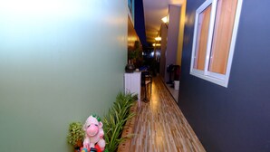 A narrow hallway with a wooden floor, a decorative sheep sculpture, and a window with blinds. - Lanta at Lanta Place (Ko Lanta)