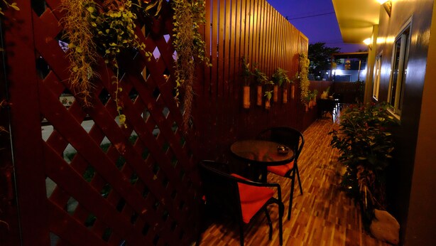 A wooden deck with a red lattice fence, a round table, and chairs. - Lanta at Lanta Place (Ko Lanta)