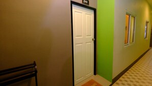 A hotel corridor with a white door marked "013", a bench, and a welcome mat. - Lanta at Lanta Place (Ko Lanta)