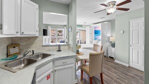 Una cucina con mobili bianchi, un lavello doppio e una ventola a soffitto.