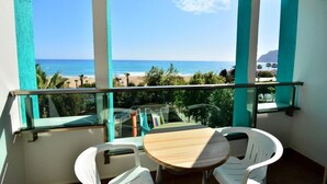 Un balcon avec vue sur l’océan, une table et deux chaises.