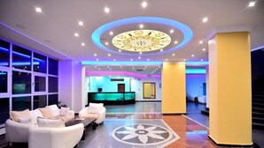 Un hall d’hôtel comprenant un comptoir d’accueil, un espace salon et un plafond décoratif.