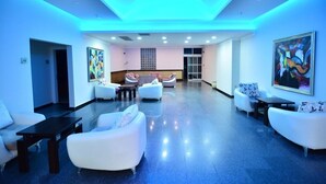 Un hall d’entrée moderne avec des canapés blancs, un comptoir d’accueil et des œuvres d’art accrochées aux murs.