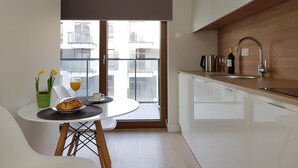 A modern kitchen with a white countertop, stainless steel appliances, and a wooden backsplash. - Chopin Apartments Union (Warsaw)
