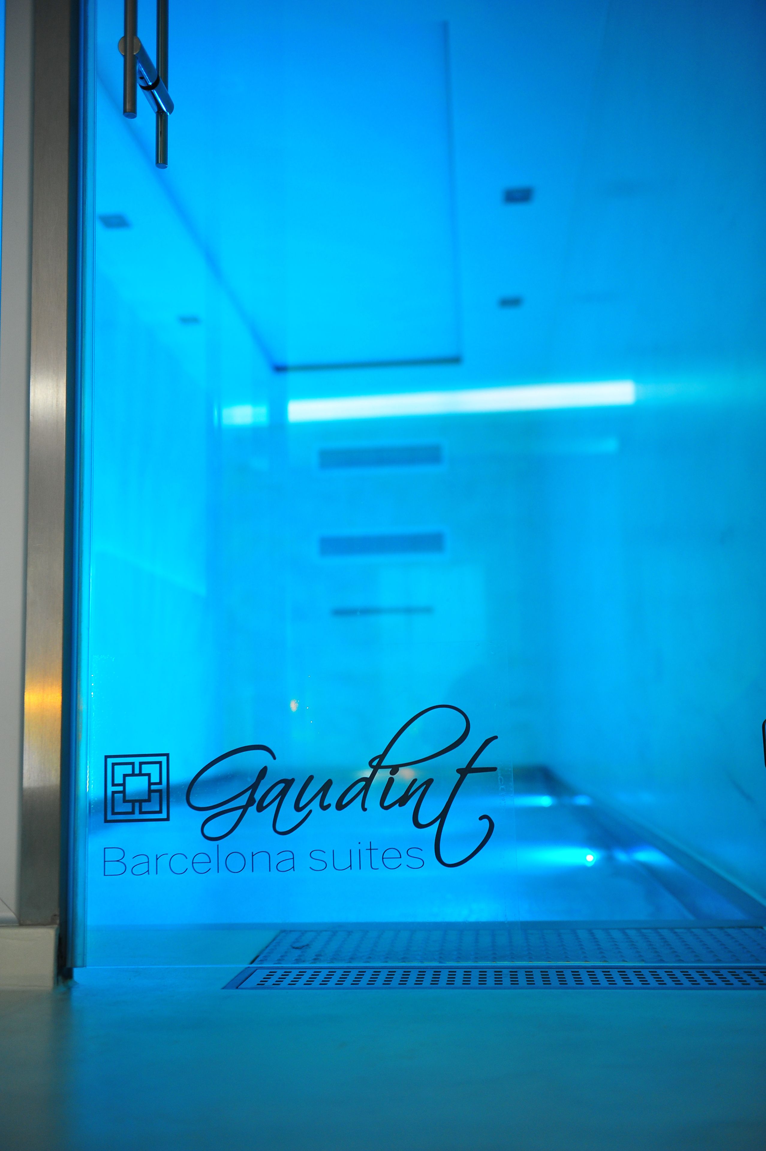 A blue-lit corridor with a sign reading "Gaudint Barcelona suites."
