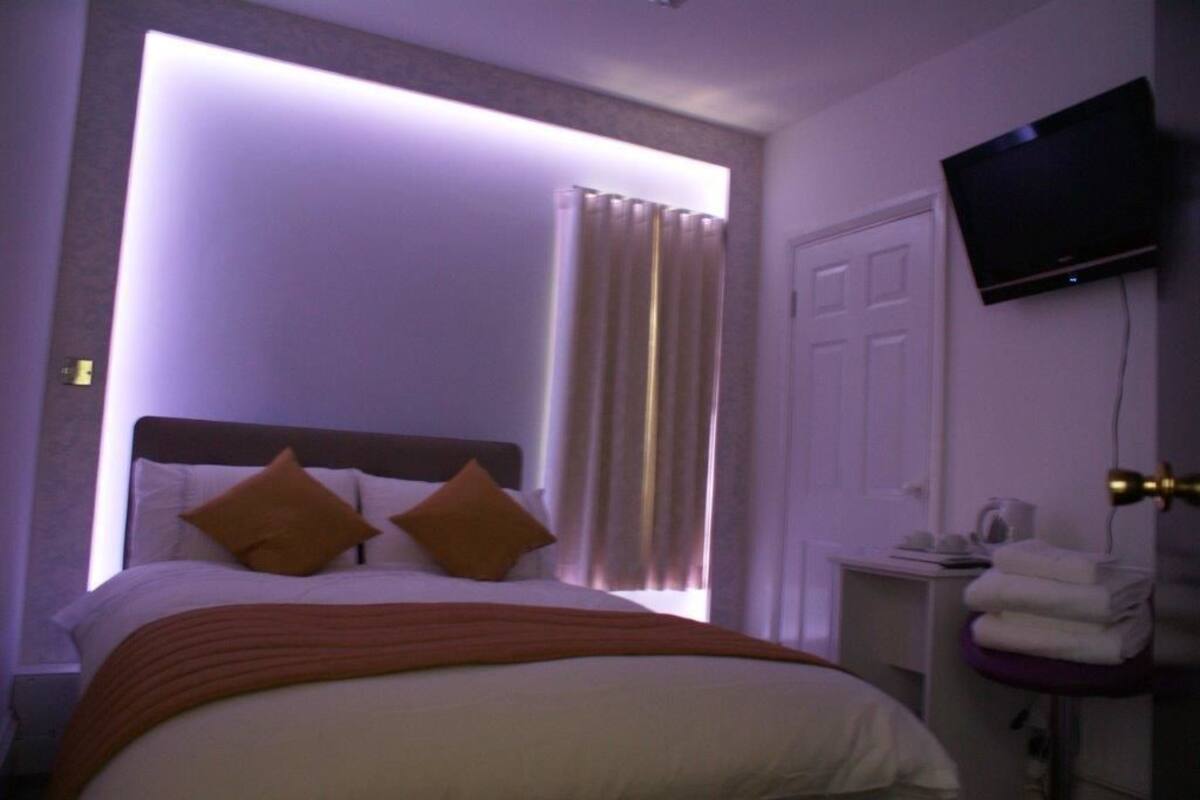 Ein Hotelzimmer mit Bett, Vorhängen, einem Fernseher und einem kleinen Tisch mit Handtüchern.