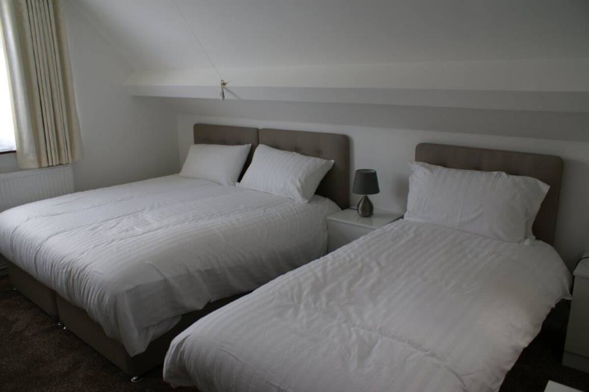 Zwei Einzelbetten mit weißer Bettwäsche in einem schlichten, sauberen Zimmer.