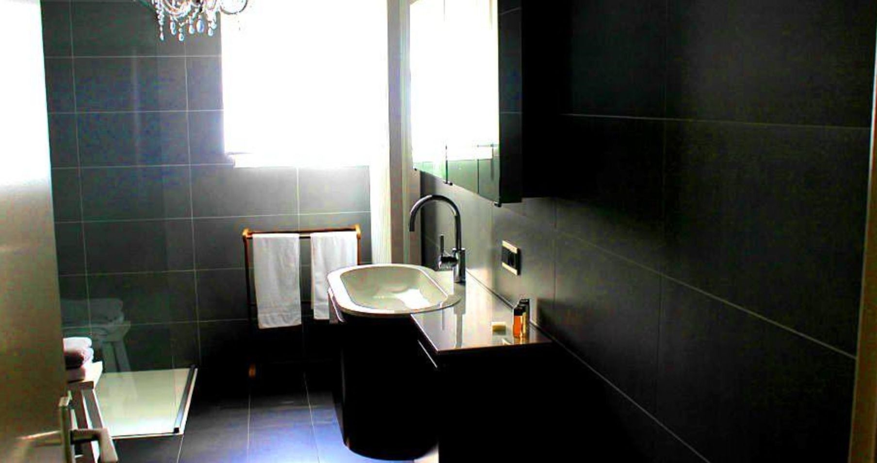 Een moderne badkamer met een wastafel, spiegel en handdoekhouder.