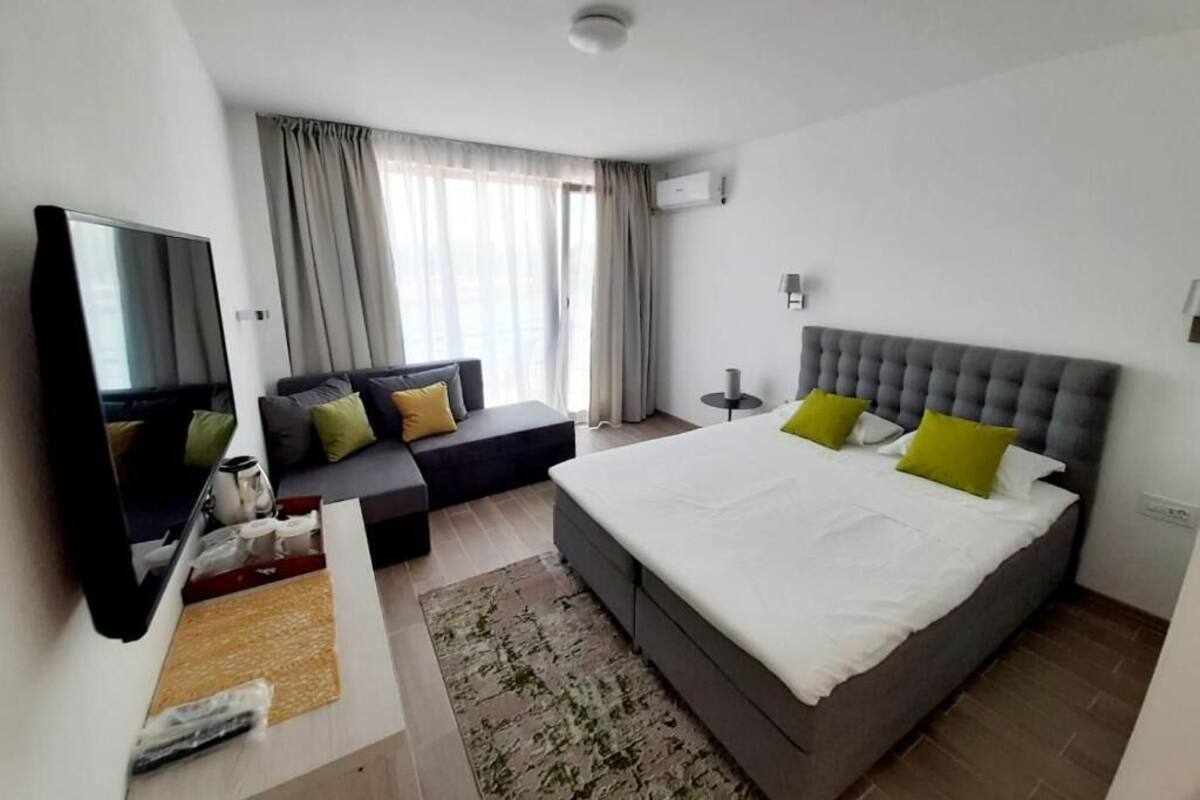 Una habitación de hotel moderna con una cama grande, un sofá, un televisor y una ventana con cortinas.