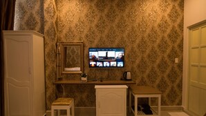 Una habitación con televisión montada en la pared, una mesita, un armario y una silla.