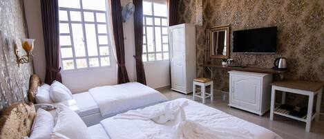 Habitación de hotel con dos camas, televisión, armario y una mesita con tetera.