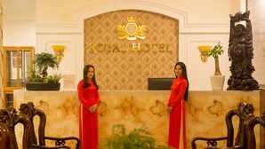 Un mostrador de recepción en el Hotel Royal, con dos empleados uniformados de rojo.