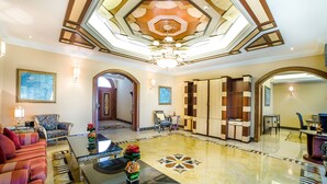 A spacious lobby with a high ceiling, a chandelier, and a large mirror. There are seating areas with sofas and armchairs, and a coffee table with a vase of flowers. - Al Raha Beach Hotel Villas (Abu Dhabi)