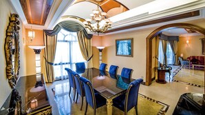 A luxurious dining room with a glass table, blue upholstered chairs, and ornate ceiling details. - Al Raha Beach Hotel Villas (Abu Dhabi)