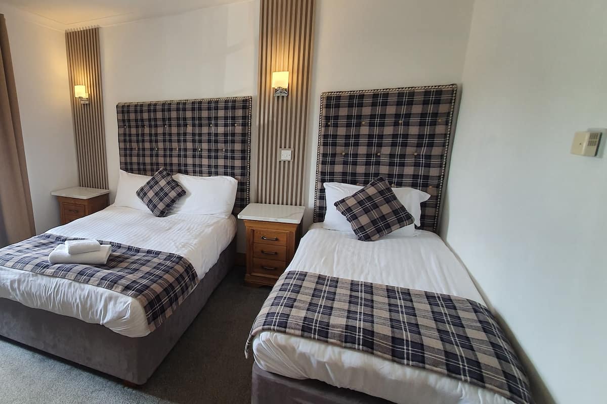 Une chambre d’hôtel avec deux lits, une chaise et une table de chevet.