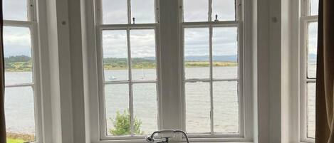 A bathroom with a bathtub and a view of a lake through large windows.