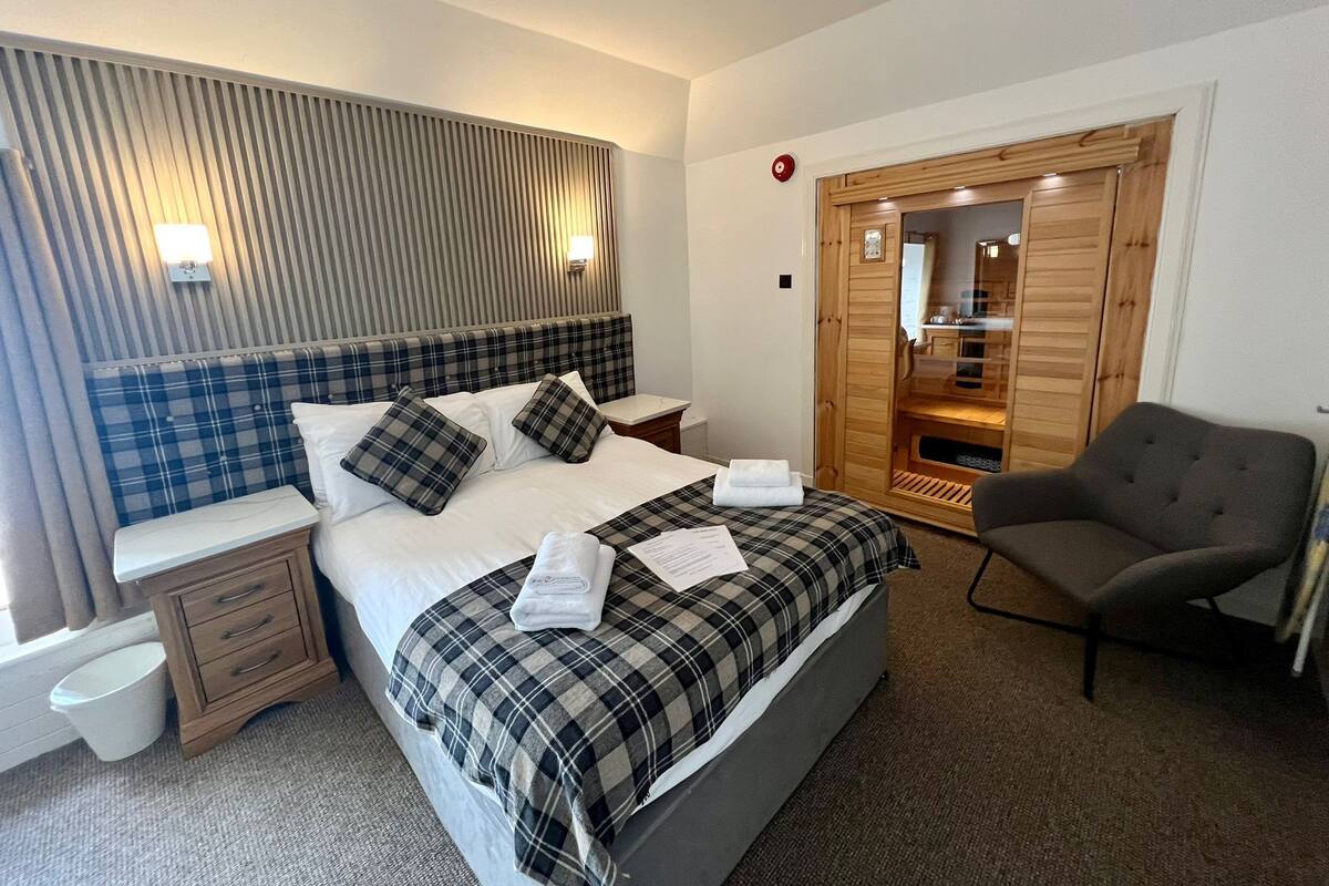 Une chambre d’hôtel moderne avec un grand lit, une armoire en bois, une chaise et une table de chevet.