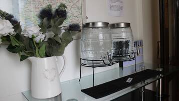 A reception area with a white vase of flowers, a keyboard, and two water dispensers on a glass counter.