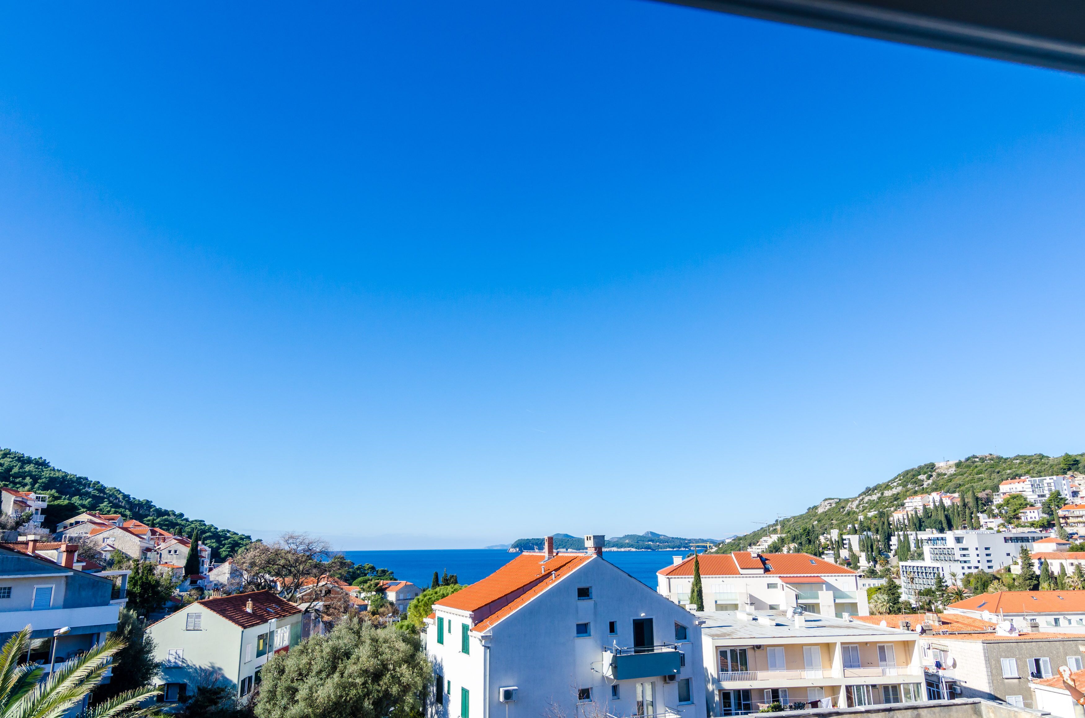 A coastal town with buildings, a clear blue sky, and a view of the sea.