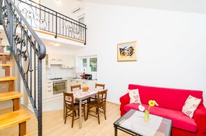 Ein modernes Apartment mit Küche, Essbereich und einem roten Sofa.