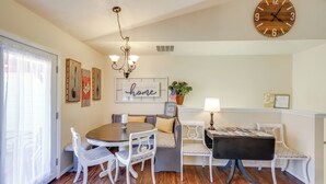 A dining area with a round table, white chairs, a chandelier, and a wooden clock on the wall. - Bitterroot Mountain Views: Montana Family Home! (Hamilton)