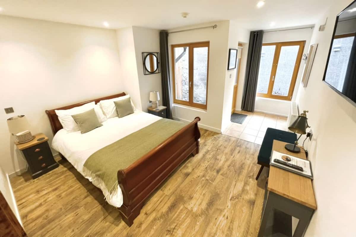 Un dormitorio con una cama de madera, mesitas de noche, un escritorio y una silla.